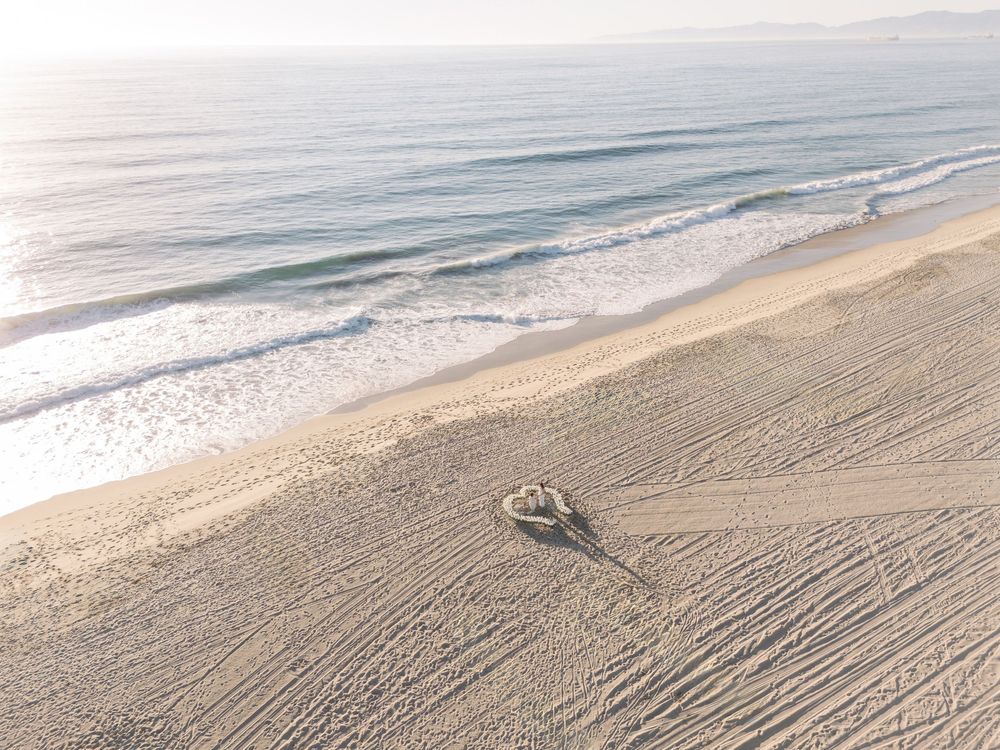 Aerial view of sandy beach shoreline with gentle waves meeting the coast on a calm day.