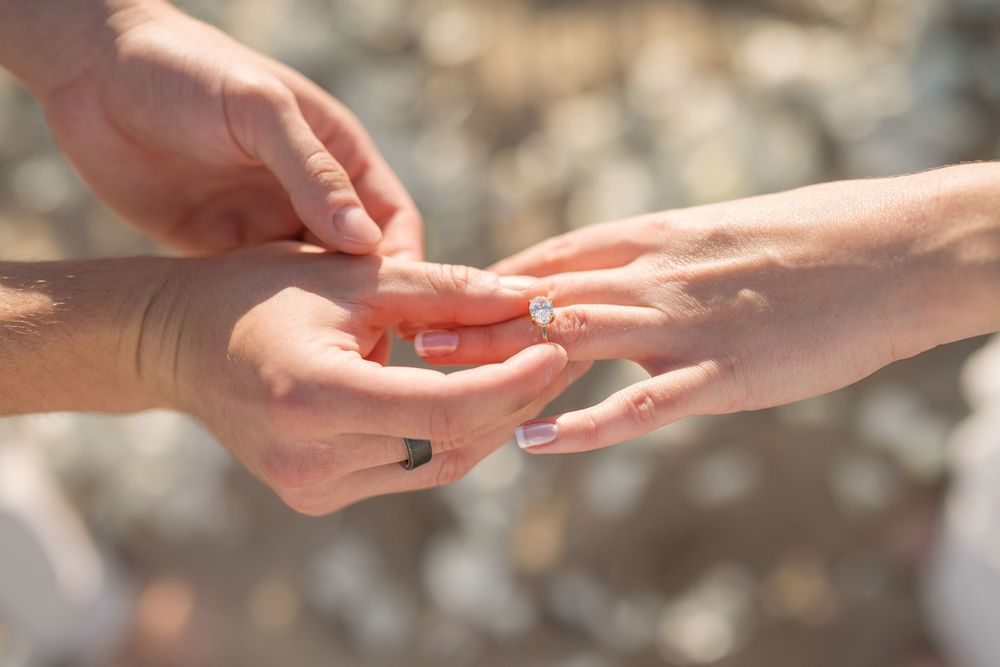 Two hands reaching towards each other in a delicate gesture against a soft blurred background.