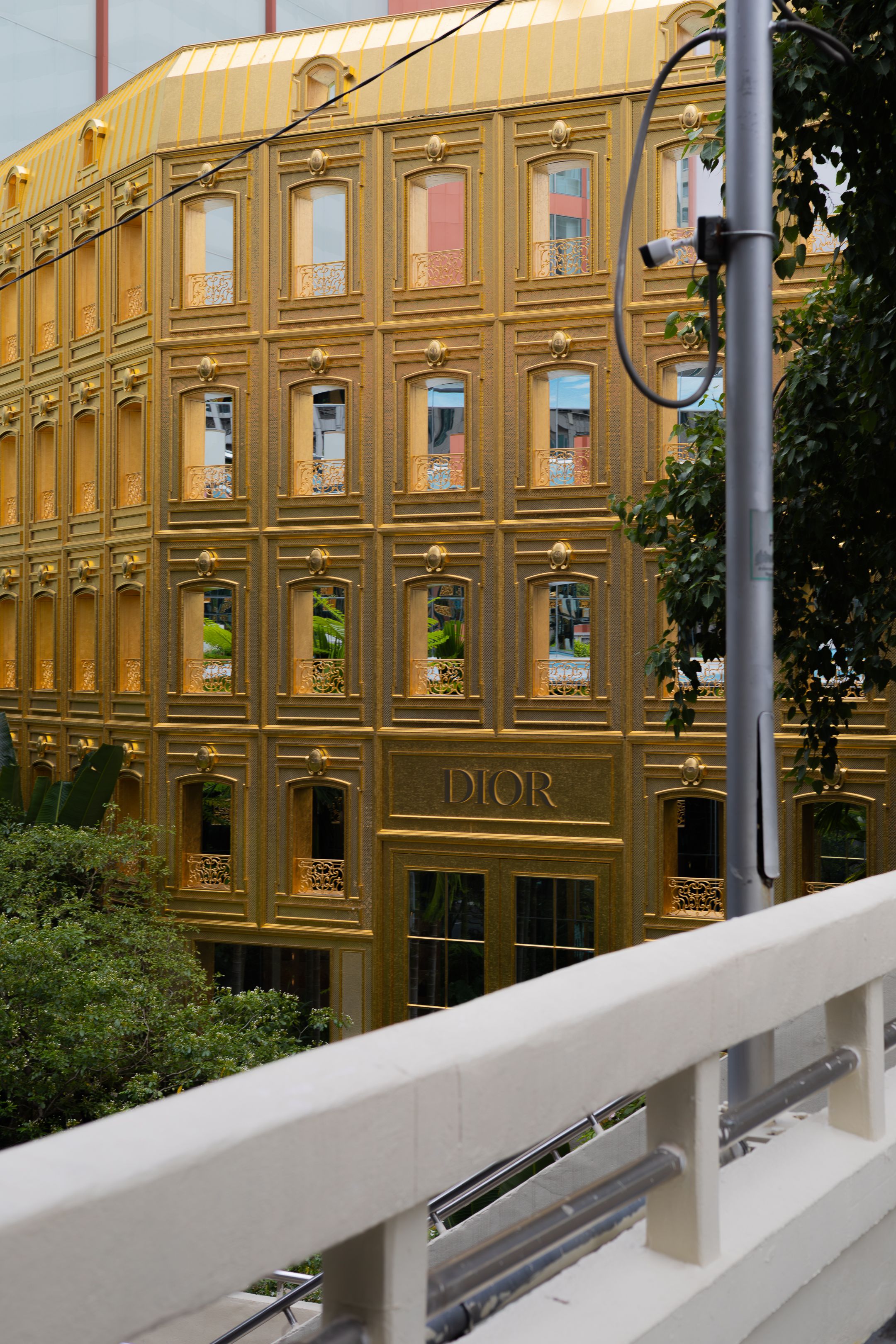 Luxurious gold-colored Dior building facade with ornate windows and architectural details in an urban setting.