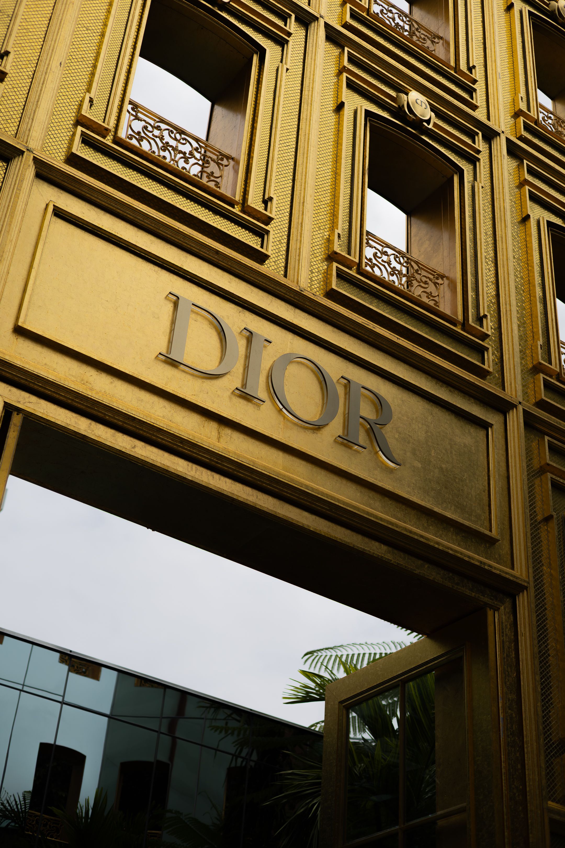Exterior view of a luxury Dior retail store facade with gold lettering and architectural details.