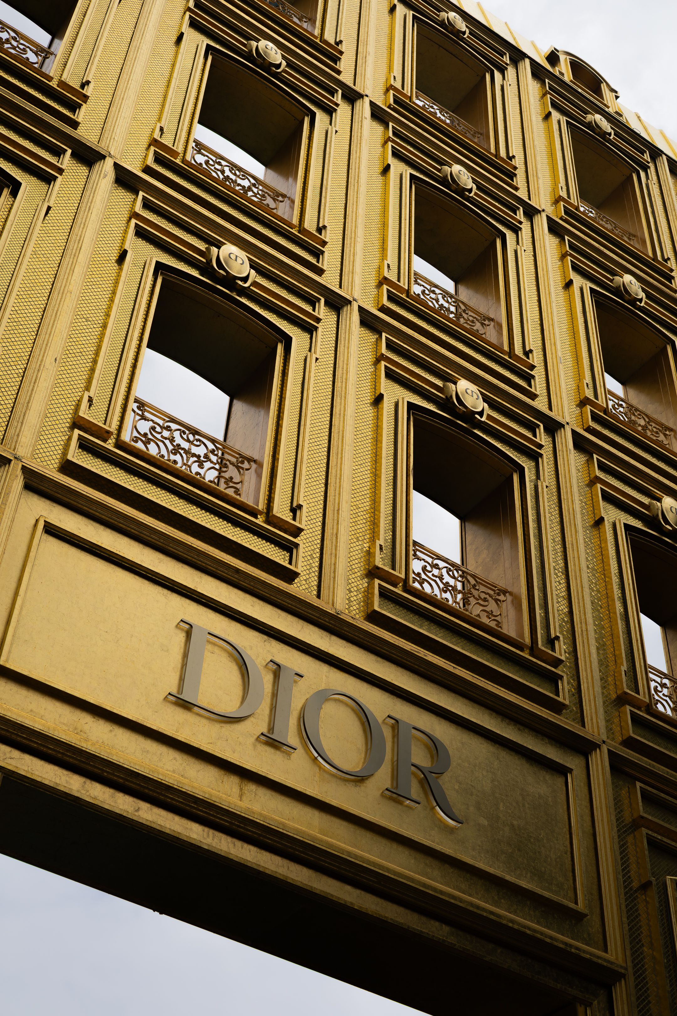 Architectural detail of an ornate building facade with repeating window patterns and decorative elements in sepia tones.