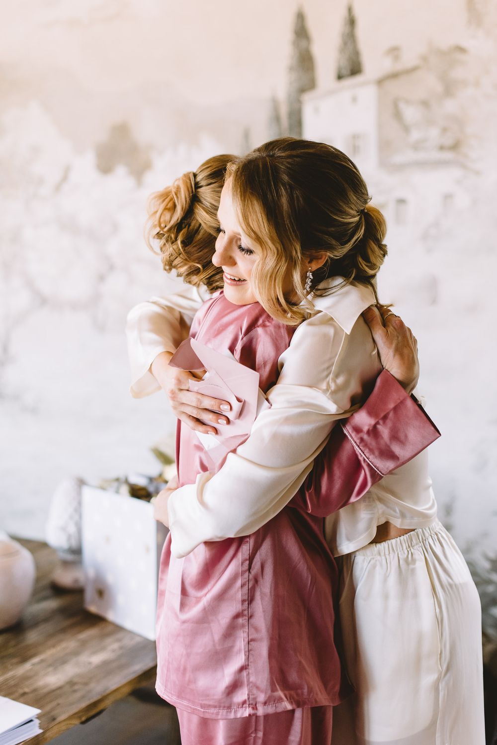 Two people embrace warmly in a sequence of photos showing a tender hug against a light colored wall.