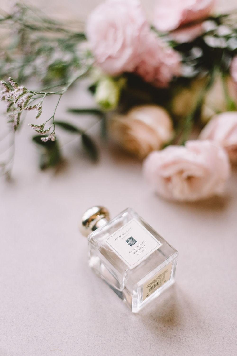 A collection of close-up shots showing delicate perfume bottles with pink flowers in soft lighting.