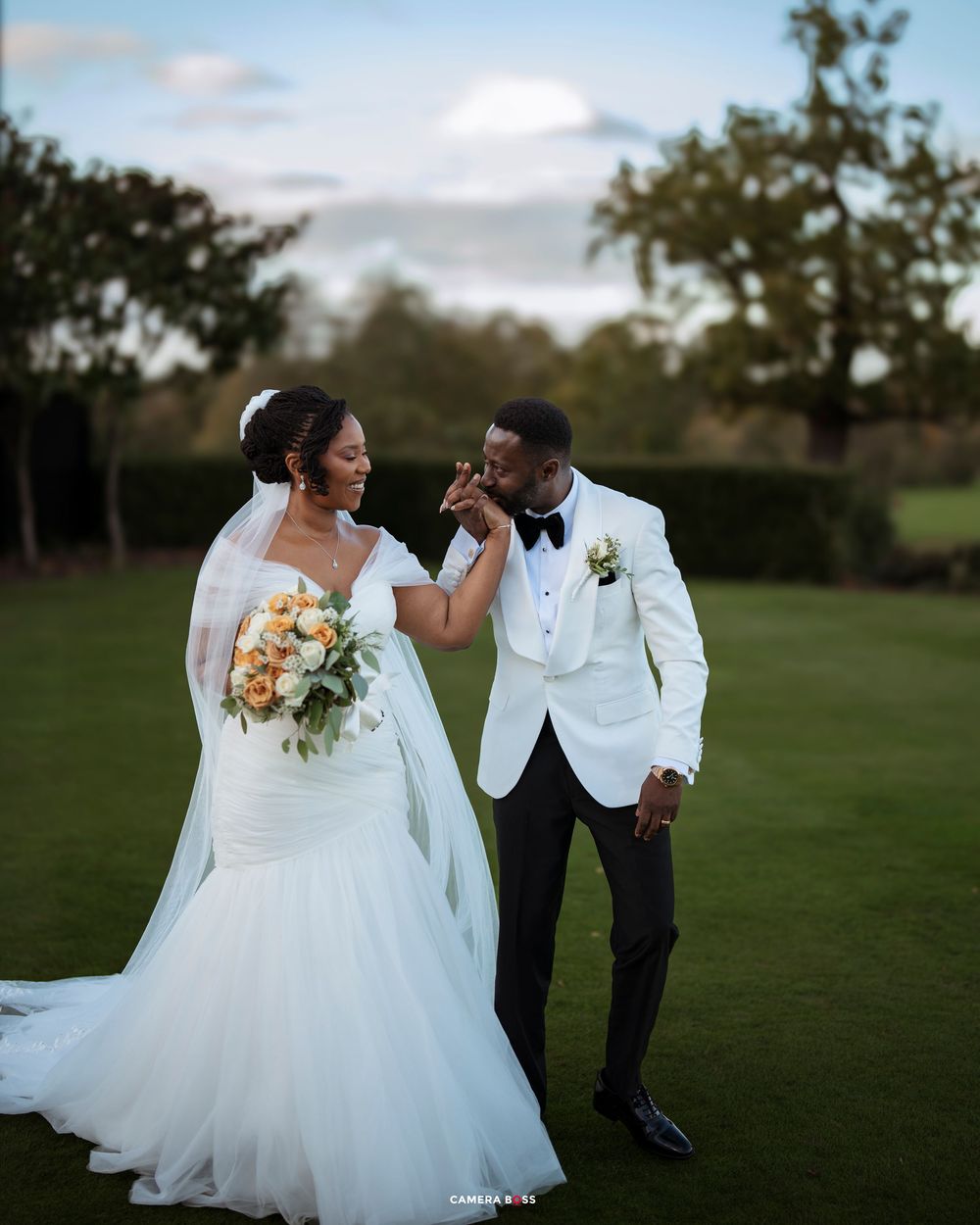 A joyful couple shares a romantic moment together on a grassy field during their outdoor wedding photo session.