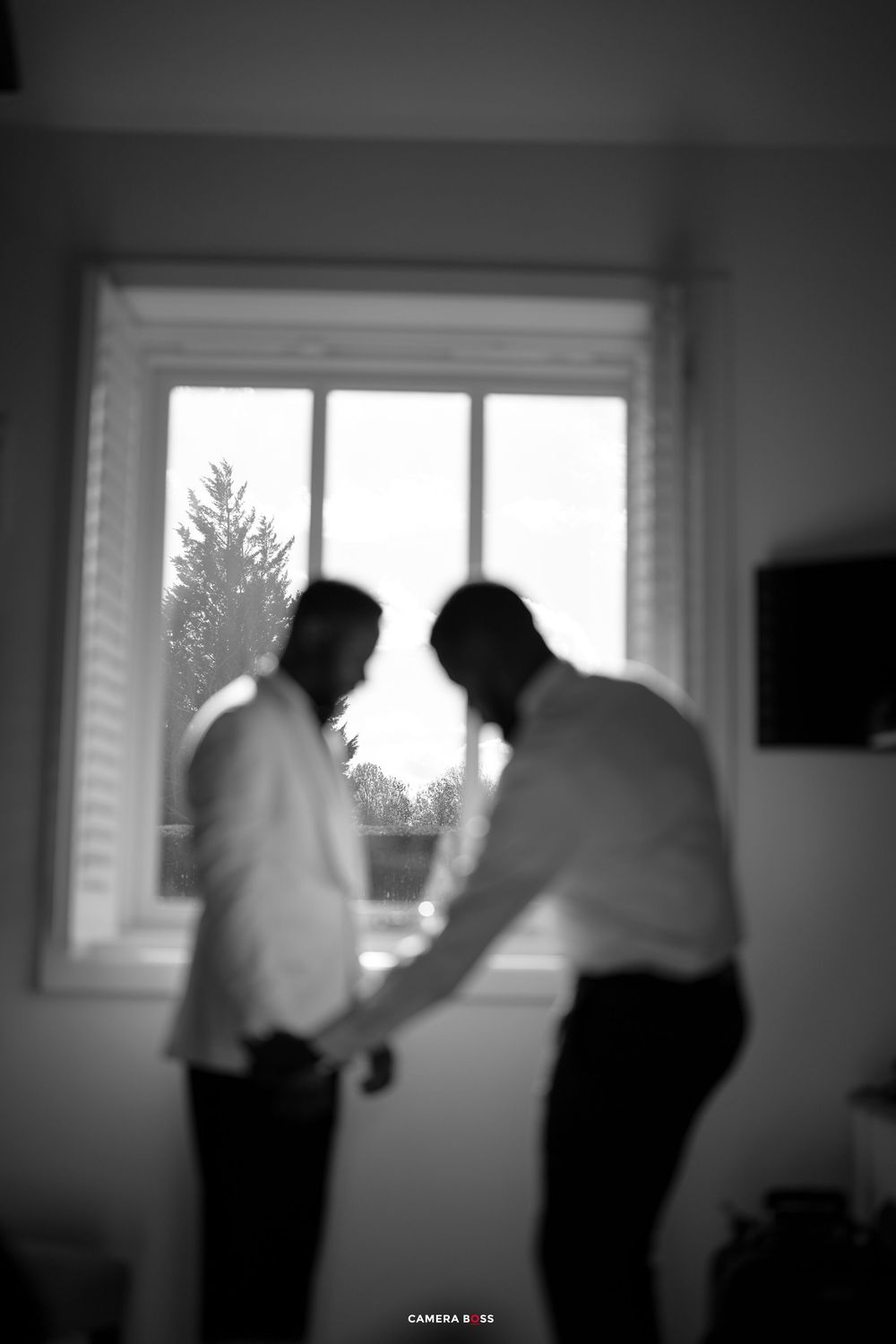 Blurry black and white sequence of people moving near a window in what appears to be an office setting.