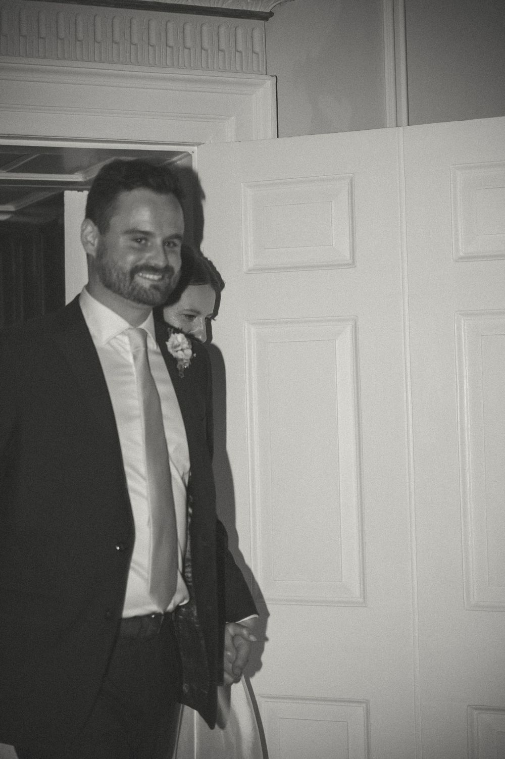 A series of black and white photos showing a person in formal attire standing near a white door.