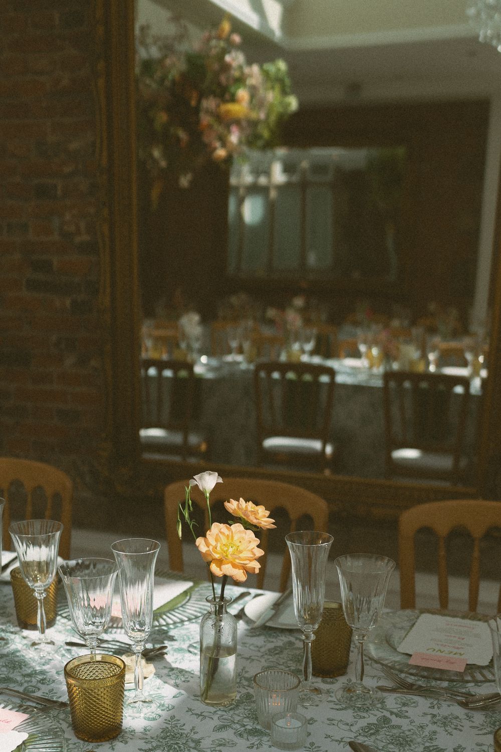Elegant table settings at a rustic wedding reception with glowing candles and floral centerpieces on white linens.