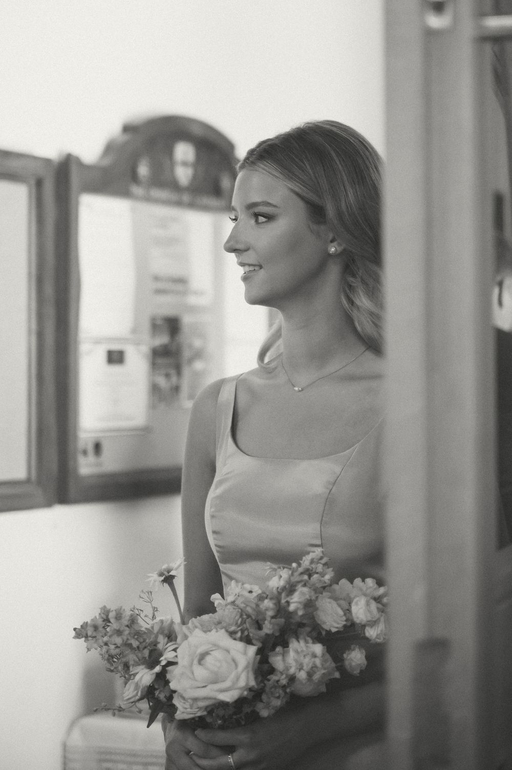 A black and white portrait of a bride holding a bouquet while looking away from the camera.