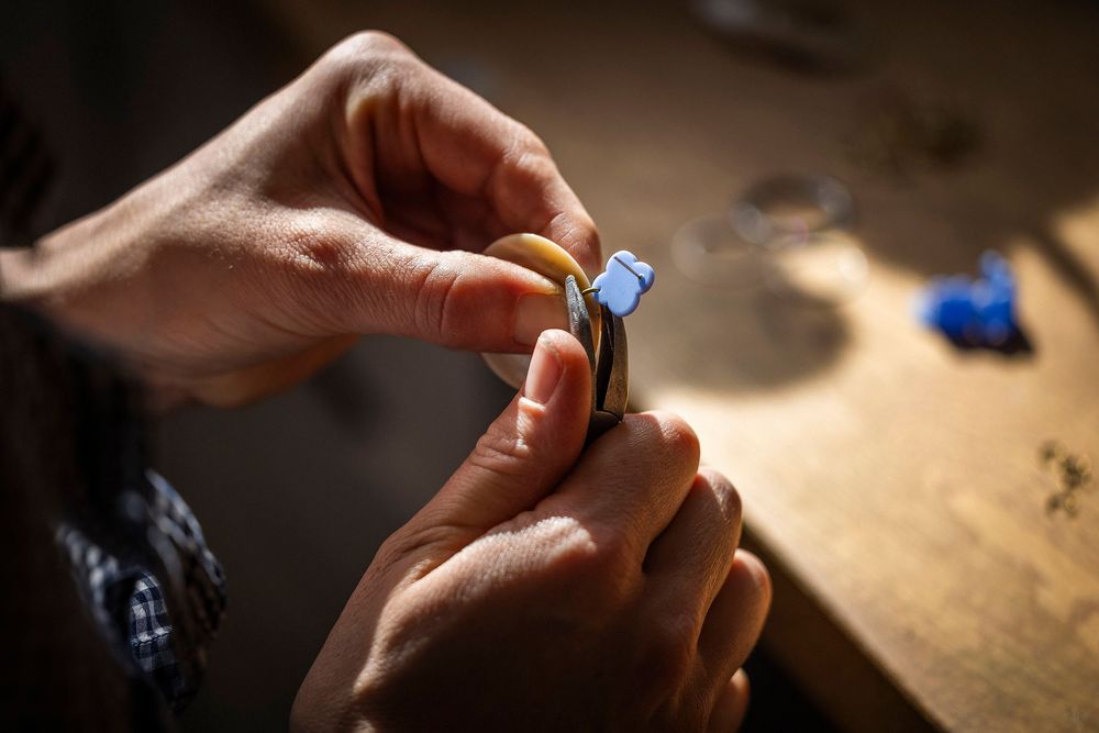 Close-up of hands holding small objects on a wooden surface in warm lighting.