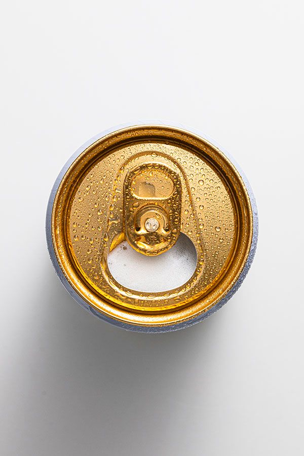 Golden beverage can top opening sequence with water droplets on metallic surface.