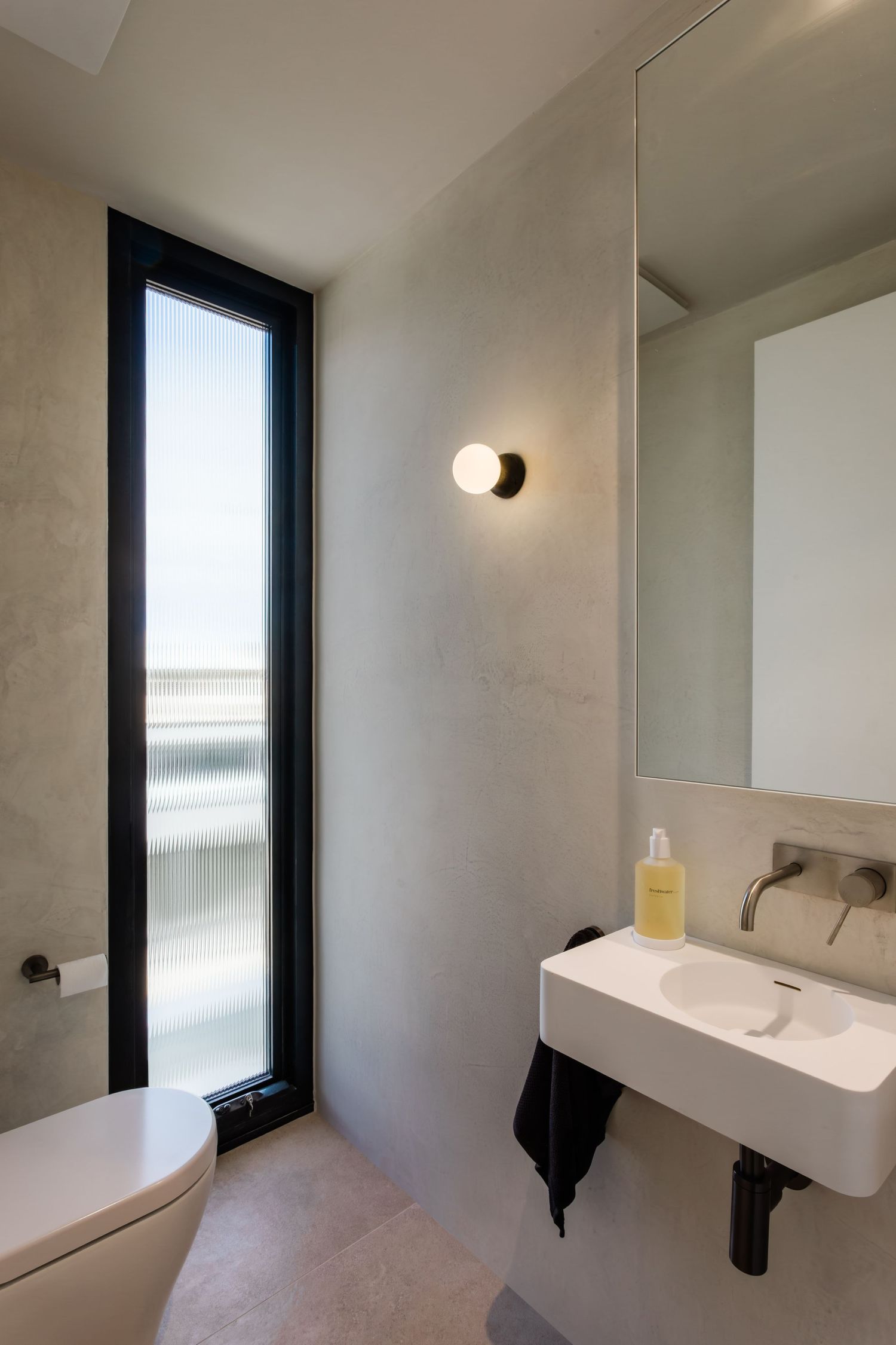 Modern minimalist bathroom interior with white walls, sleek fixtures, and natural light streaming through tall windows.
