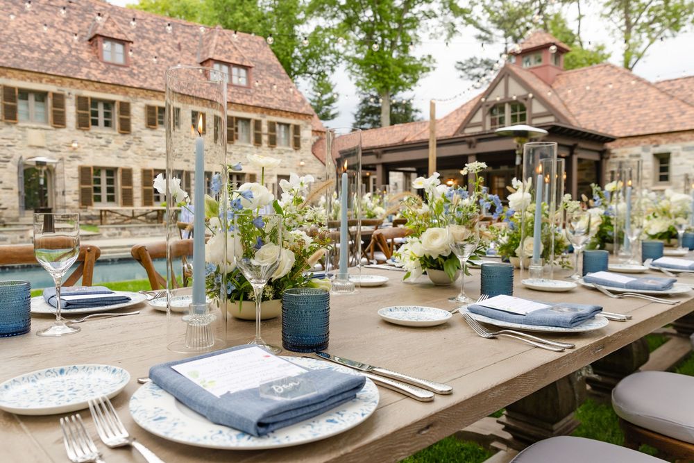 Rustic outdoor wedding venue with charming stone buildings and landscaped gardens features elegant table settings.
