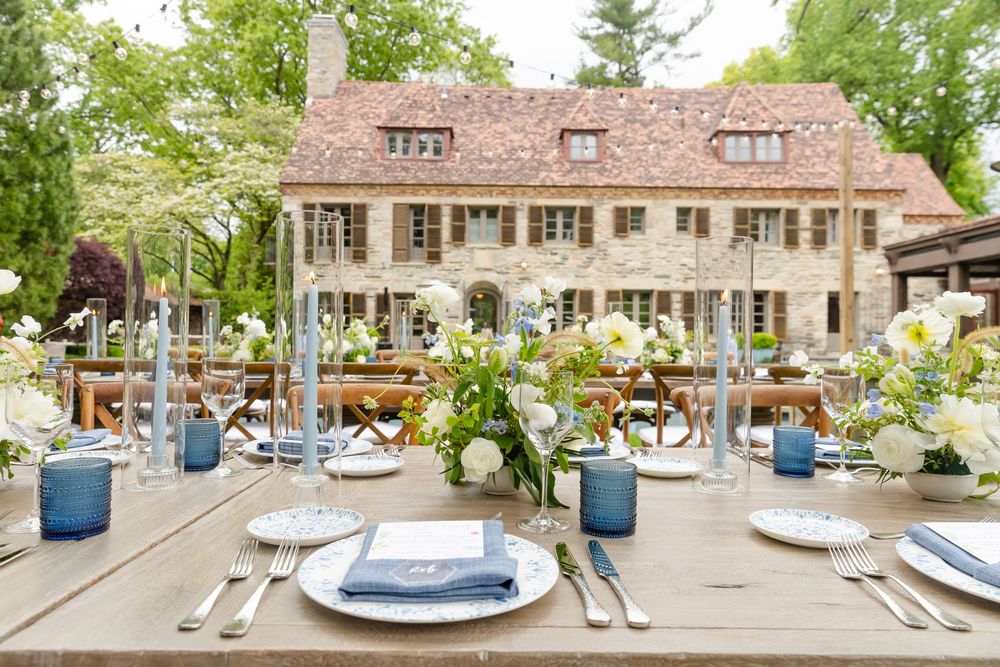 Elegant outdoor wedding table settings with blue and white decor at a rustic stone venue.