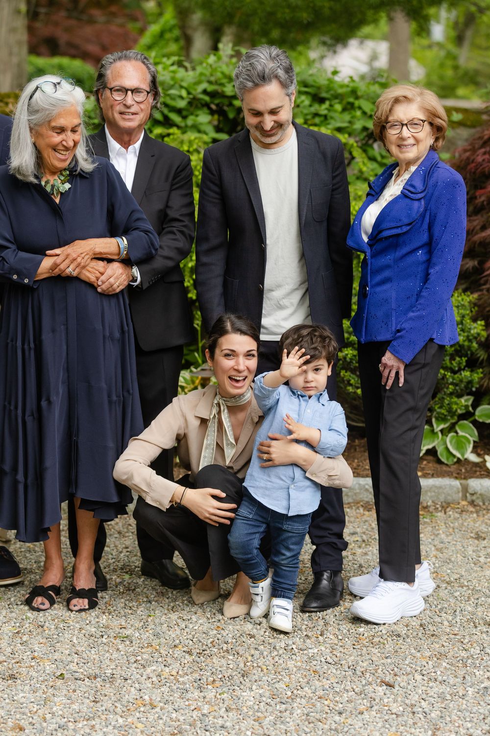 A group photo of family members in navy and blue attire gathered on a gravel surface at an outdoor celebration.