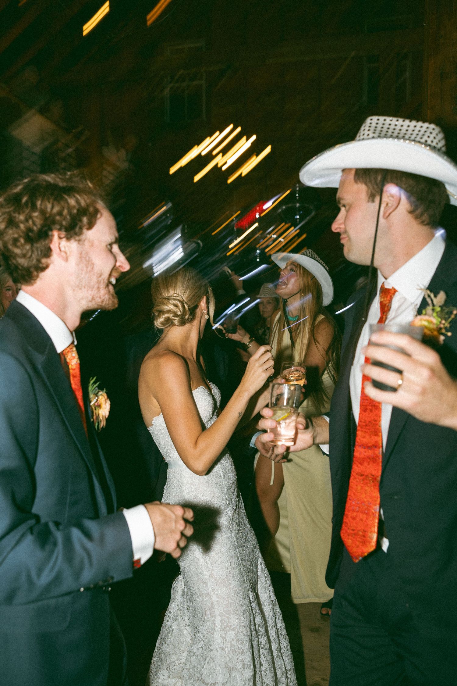 Wedding celebration candid shots showing guests dancing and enjoying drinks at night.