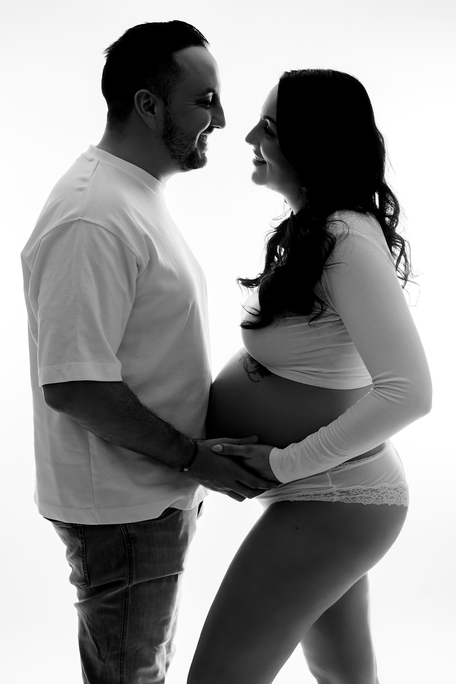 Black and white silhouette progression photo showing a pregnant woman's growing belly with partner throughout pregnancy stages.
