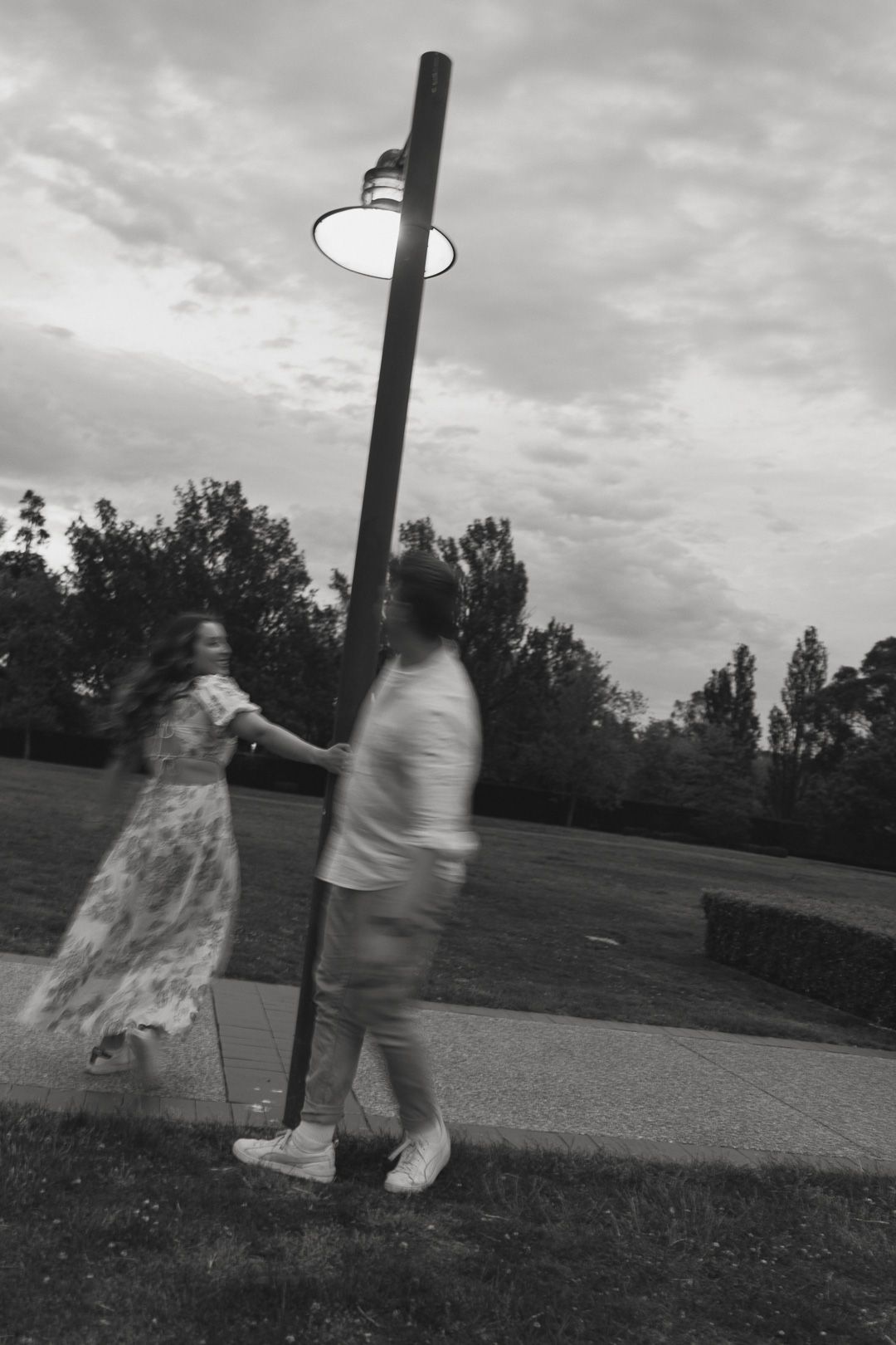 A husband and wife spinning around a light pole at sunset.