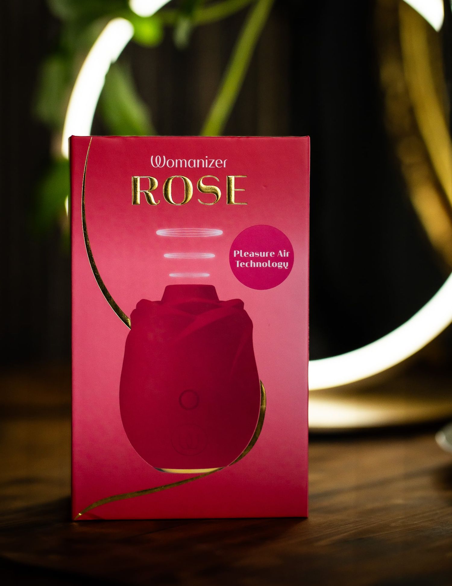 Four sequential images show a pink product box with a rose design against a dark background with blurred lights.