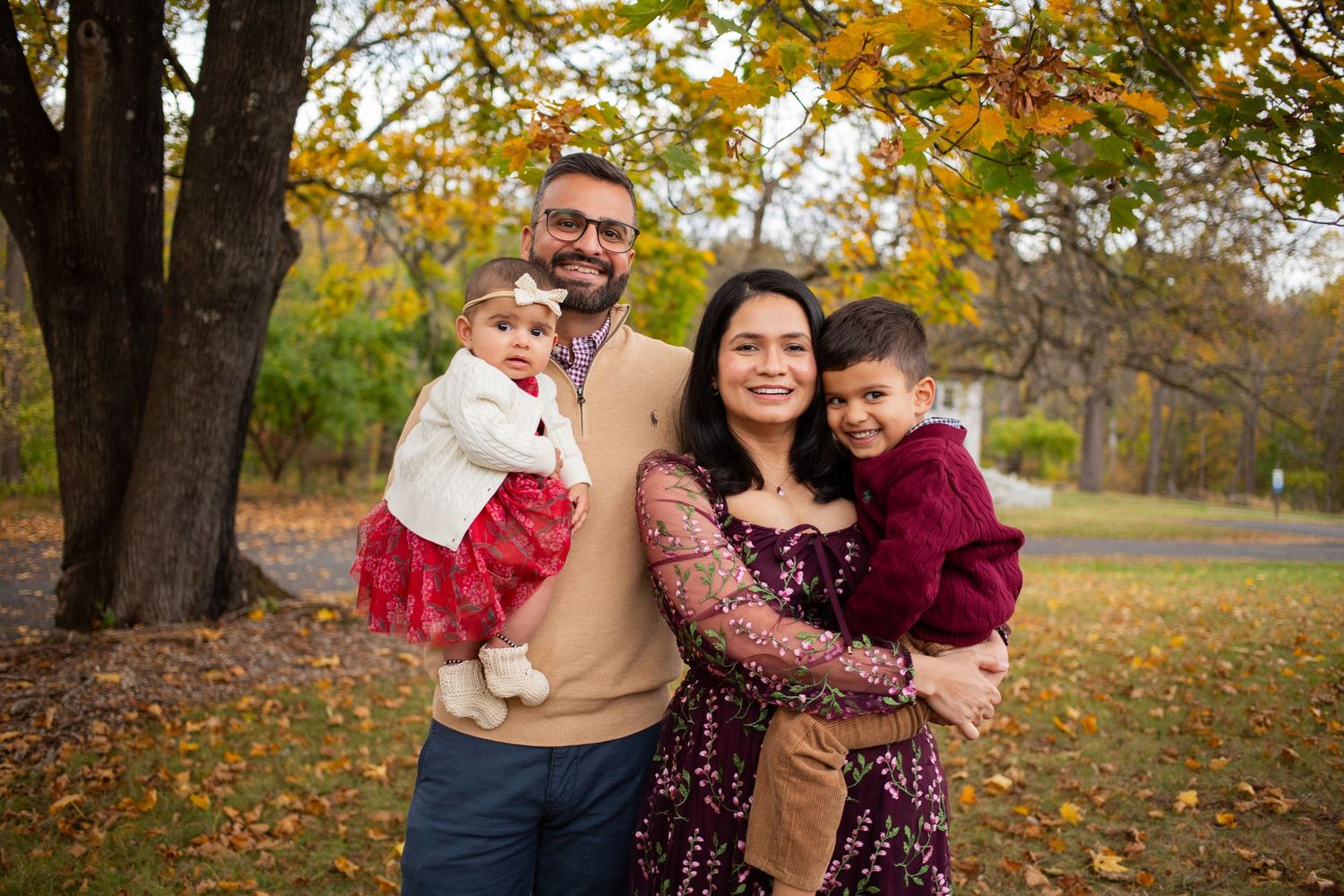 Family enjoying a fall photo session outdoors with colorful autumn leaves in the background.