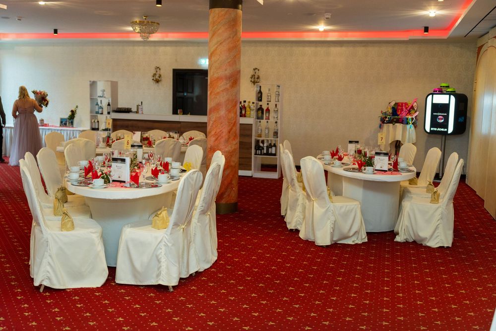 Hochzeitsfotograf Berlin – Festlich geschmückter Festsaal im Lakeside Burghotel Strausberg mit roten Teppichen und eleganten Kronleuchtern w