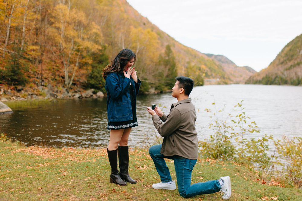 A series of romantic proposal photos captured at a scenic lake surrounded by autumn foliage in the mountains.