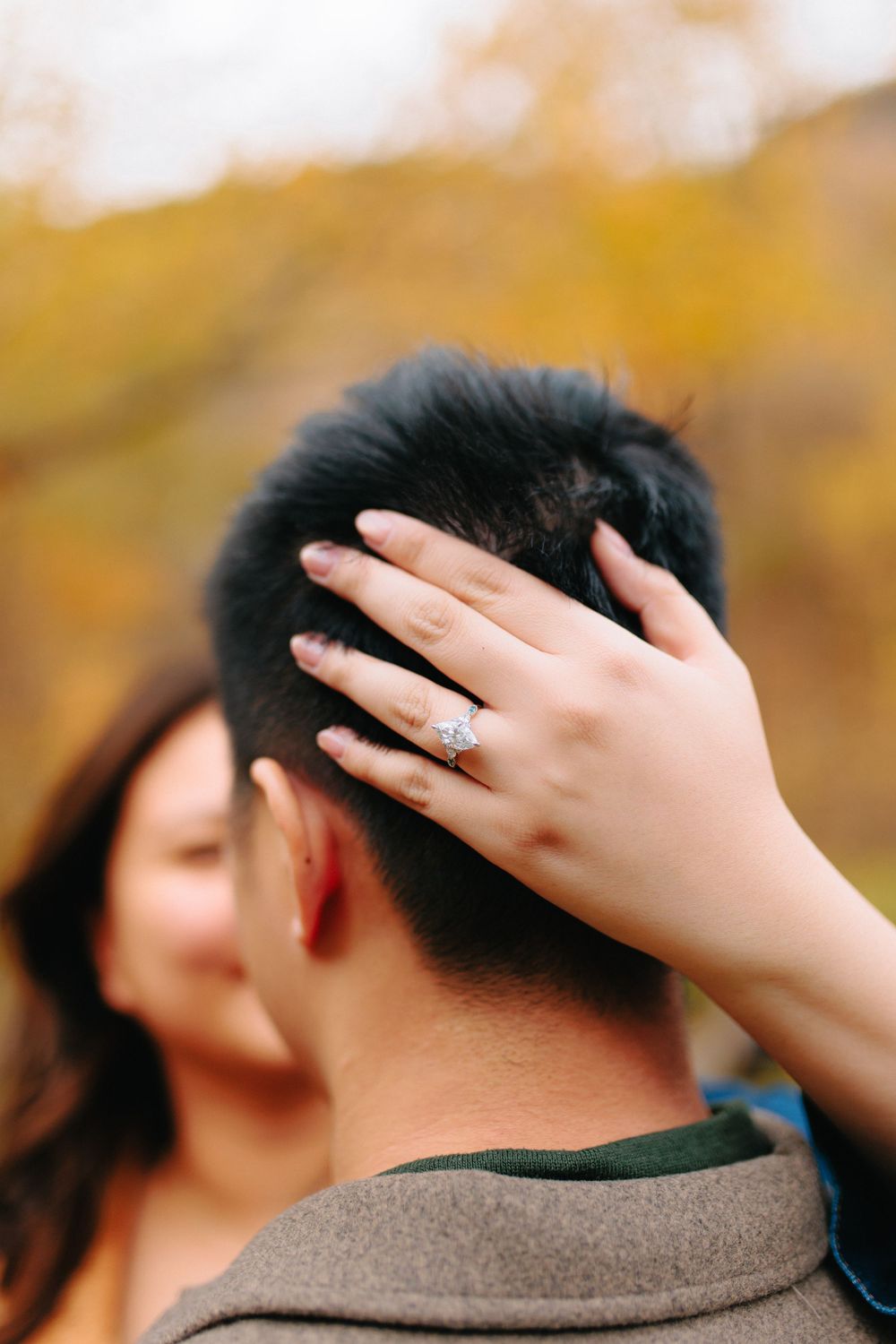 A close-up sequence of hands gently touching the back of someone's head against a warm autumn background.