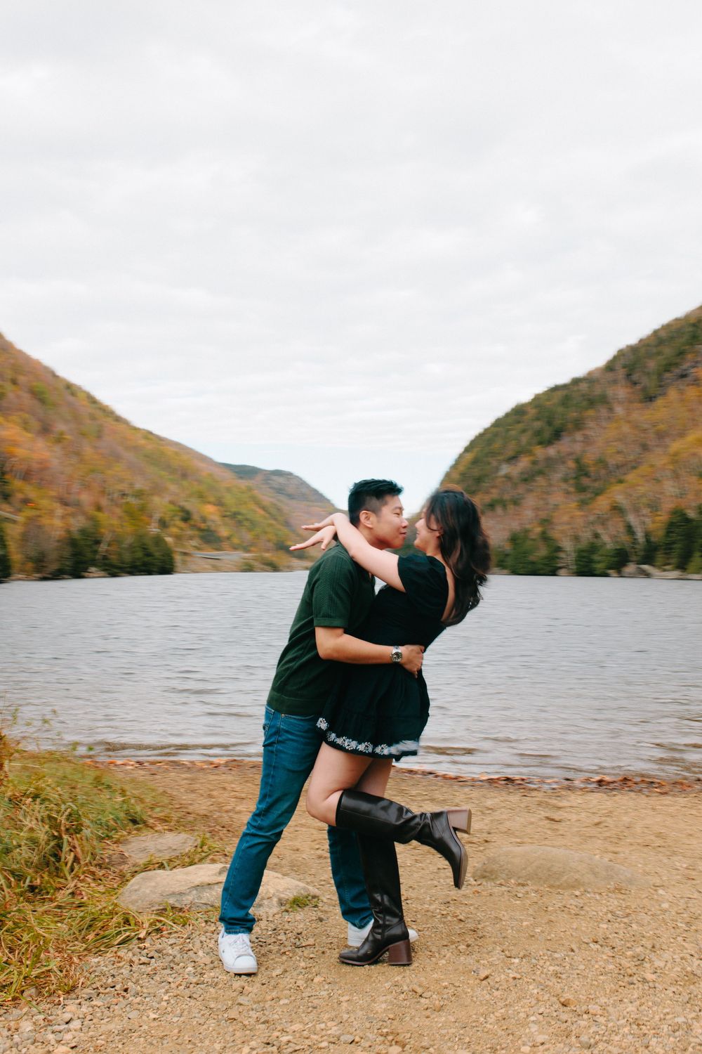 Romantic couple dances together by a scenic mountain lake during autumn.