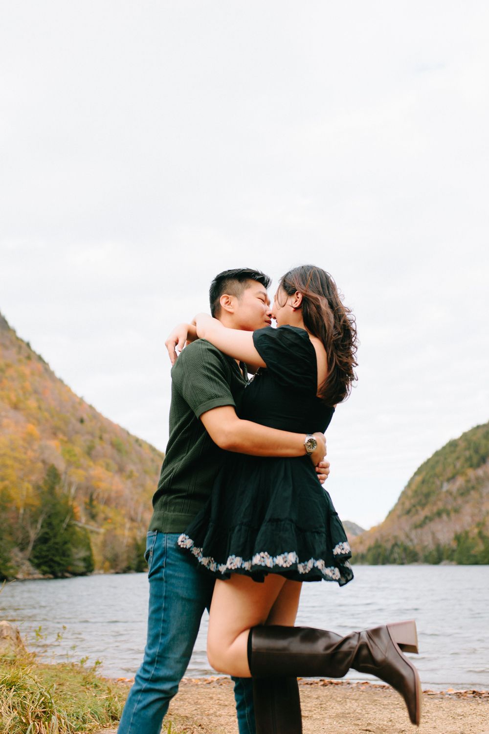 A romantic couple embraces by a scenic mountain lake during autumn, creating an intimate silhouette against nature.