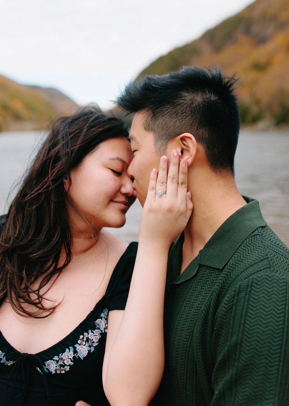 A romantic couple shares tender kisses in a series of four intimate photos by a lake with autumn mountains in the background.