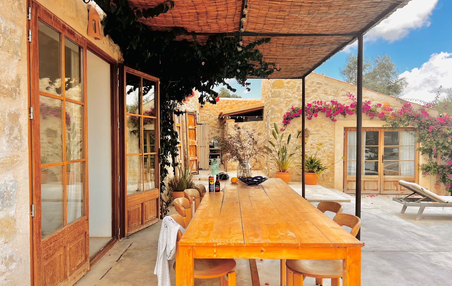 A rustic covered patio with wooden benches and orange tiled roof overlooking desert mountains in the background.