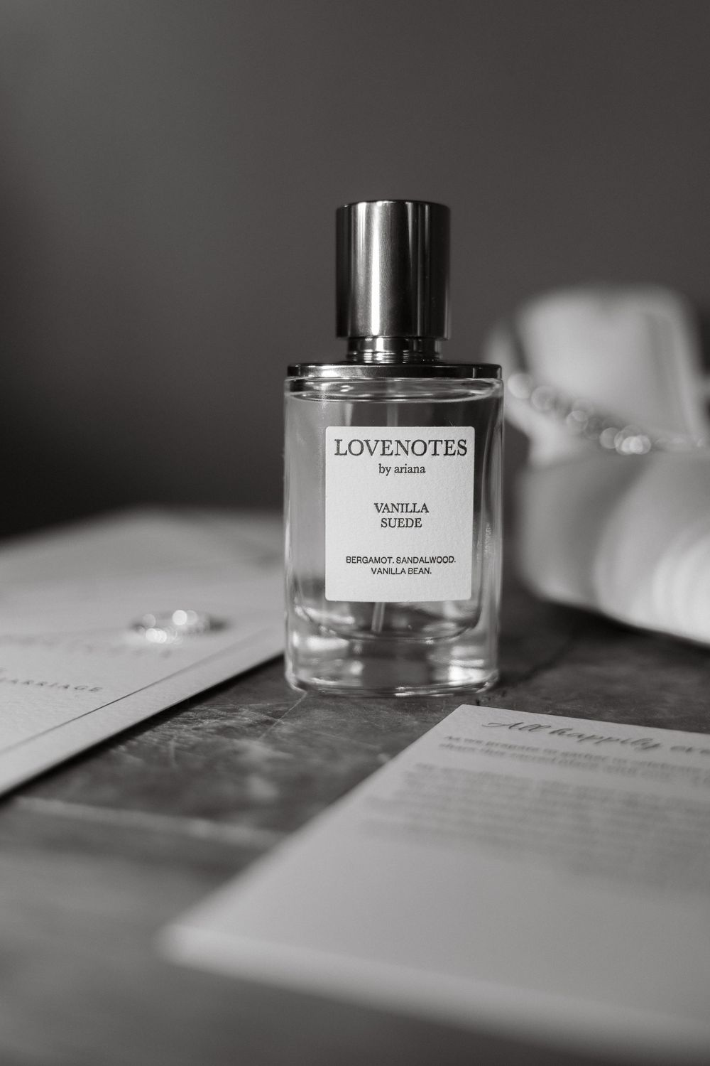 Elegant perfume bottles and love notes arranged on a table in black and white.
