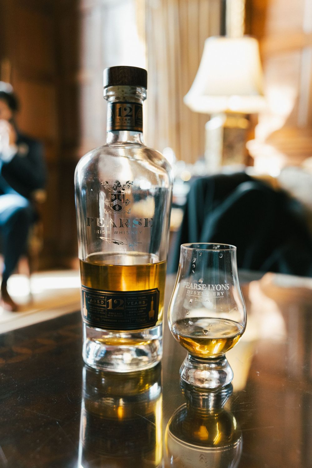 Whiskey glasses and bottles arranged on dark wooden surface in warm lighting.