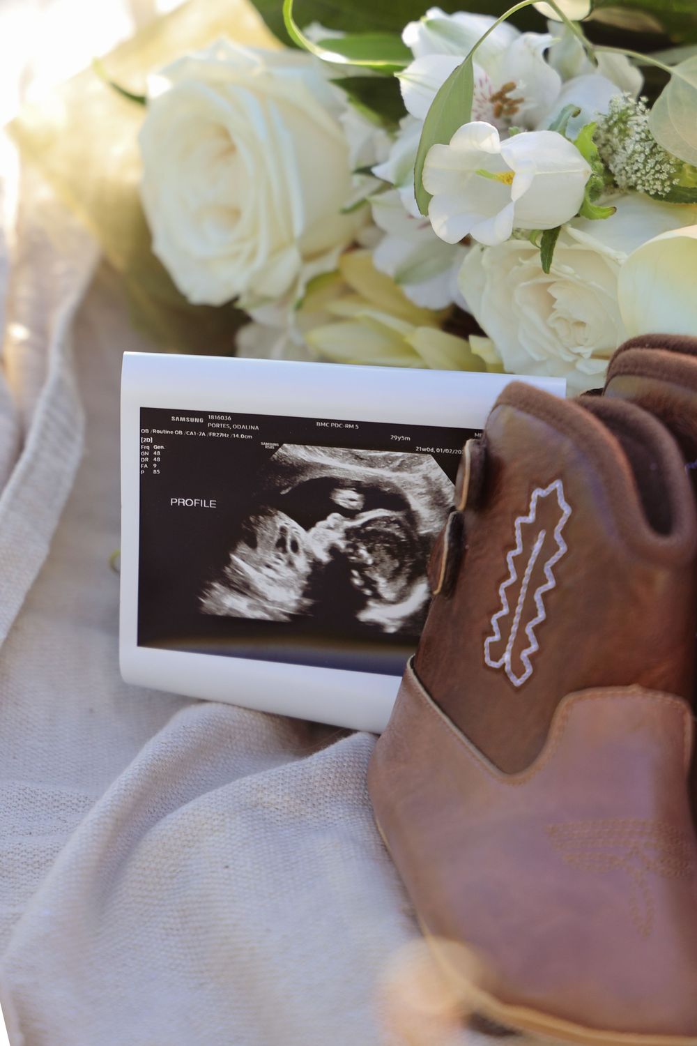 Connecticut maternity photoshoot. ultrasound photo with flowers and baby cowboy boots