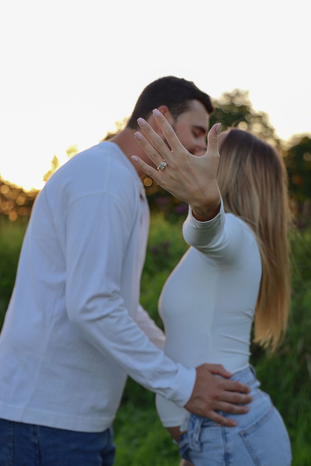 Connecticut maternity photoshoot. Couple standing in field showing off ring while kissing