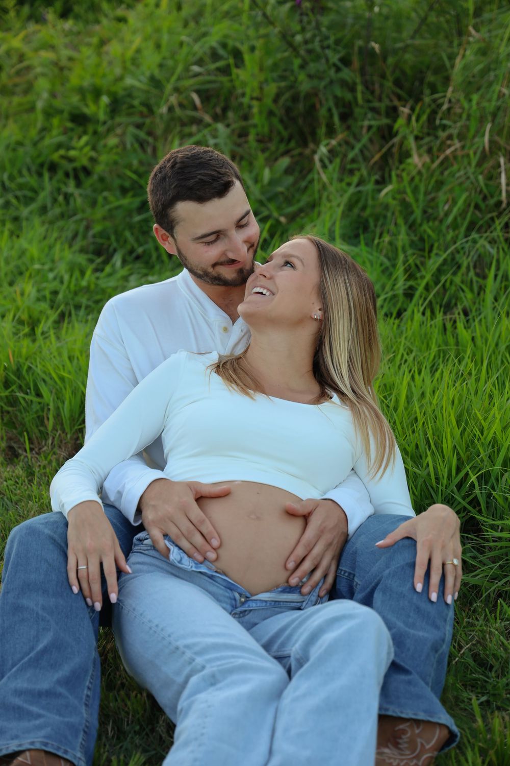 Connecticut maternity photoshoot. Couple sitting together in field
