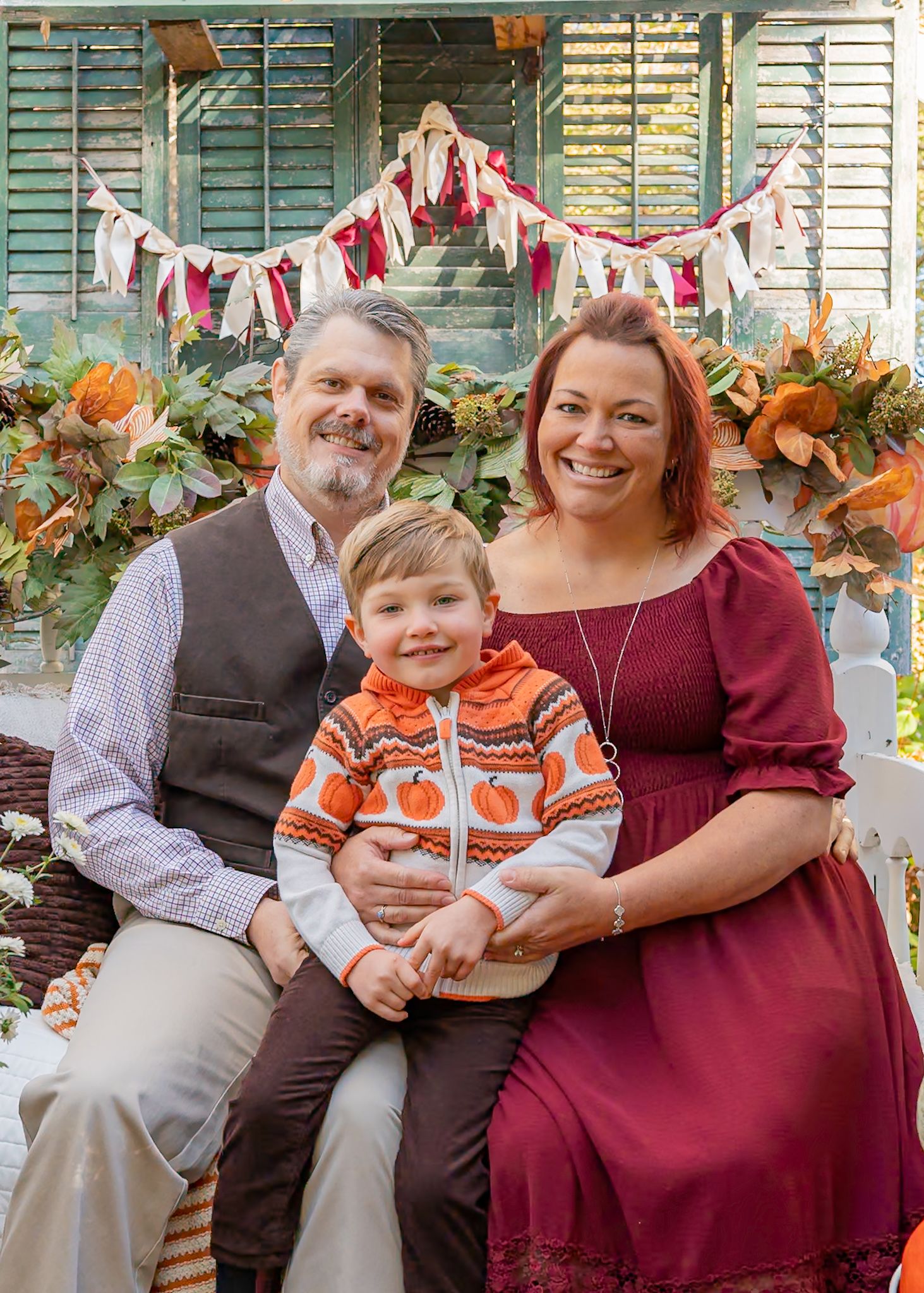 Family sitting together on a porch decorated with fall banners and autumn decor.