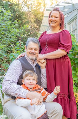 Candid family moment captured in outdoor greenhouse with autumn decor.