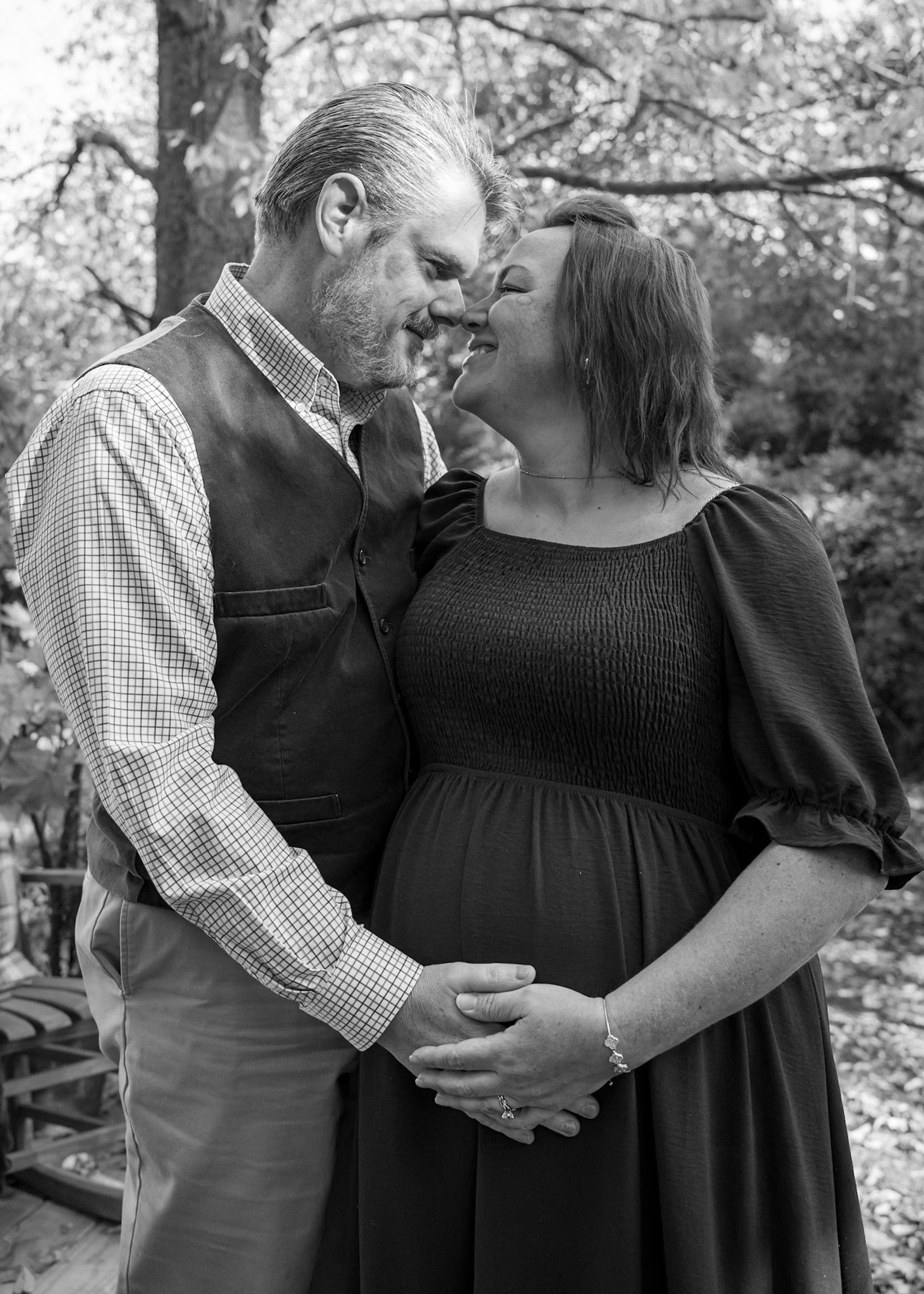 Black and white portrait of a couple sharing an intimate moment in a natural setting.