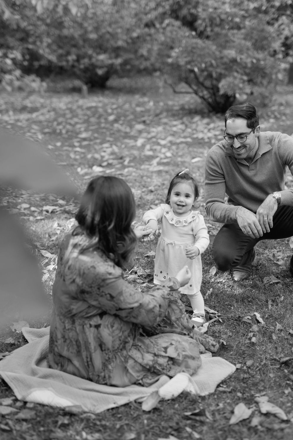 Black and white photo series showing intimate family moments on a blanket surrounded by fallen leaves.