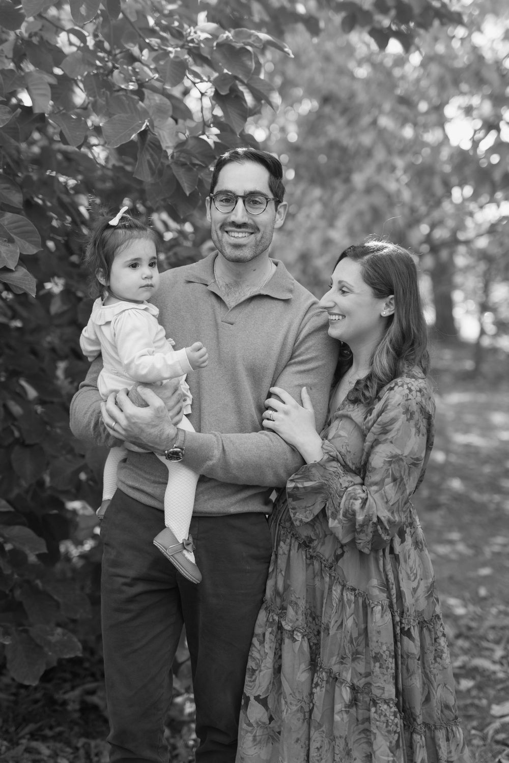 Black and white family portrait captured outdoors among trees.