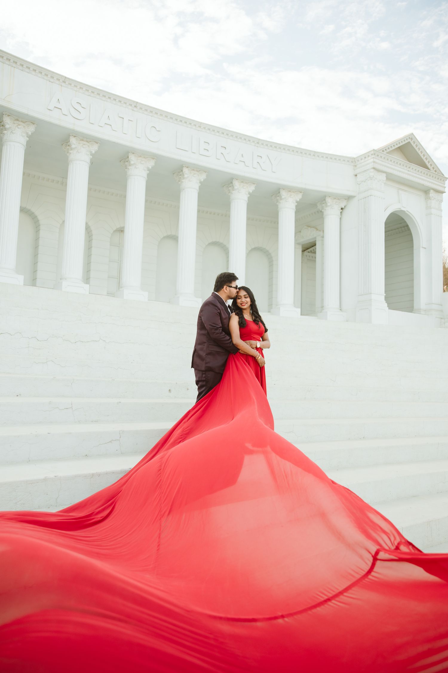 Bride in a red gown against classical architecture by Wedding Photographer in Jaipur & Wedding Photographer in Udaipur