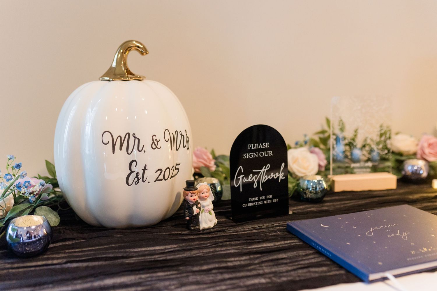 White ceramic pumpkins and decorative signs arranged on a dark wooden shelf create an elegant fall display.