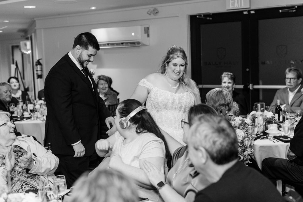 A group of people gathered at a wedding reception celebrate and dance together on the dance floor.