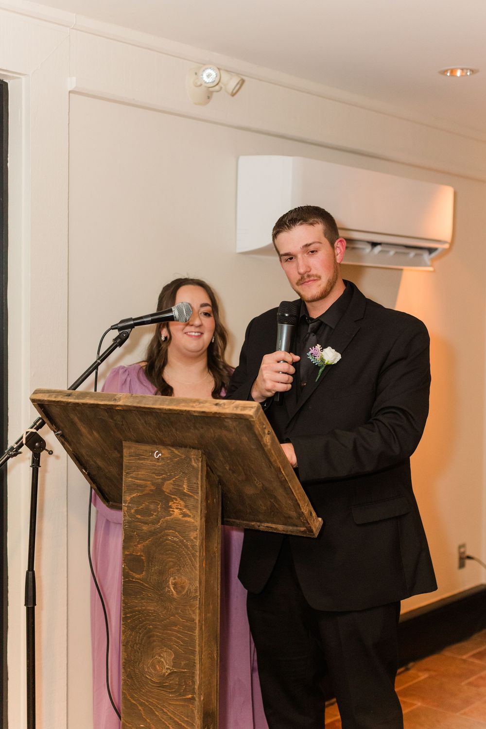 People in formal attire share a laugh at podiums during what appears to be a speaking event or ceremony.