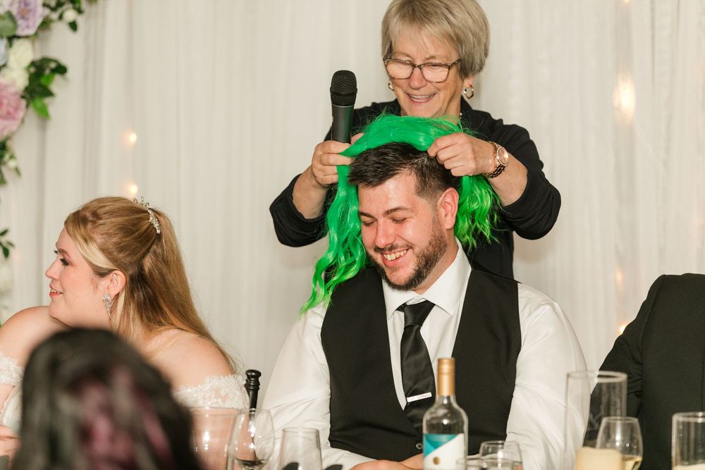 Wedding guests raise glasses in celebration during reception toasts at elegant indoor venue.