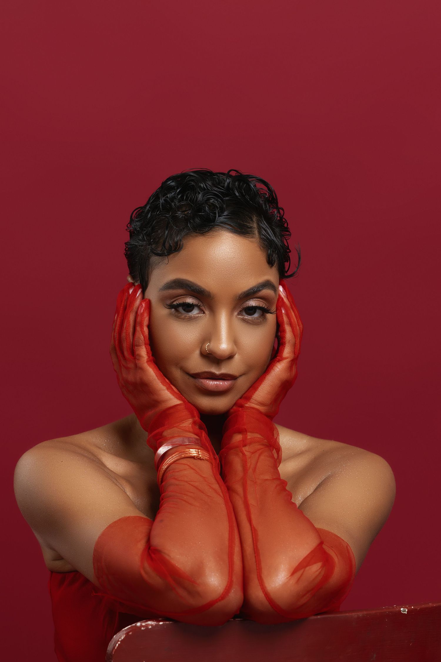 Striking fashion portrait in monochromatic red with model in lace dress posing elegantly against red backdrop.