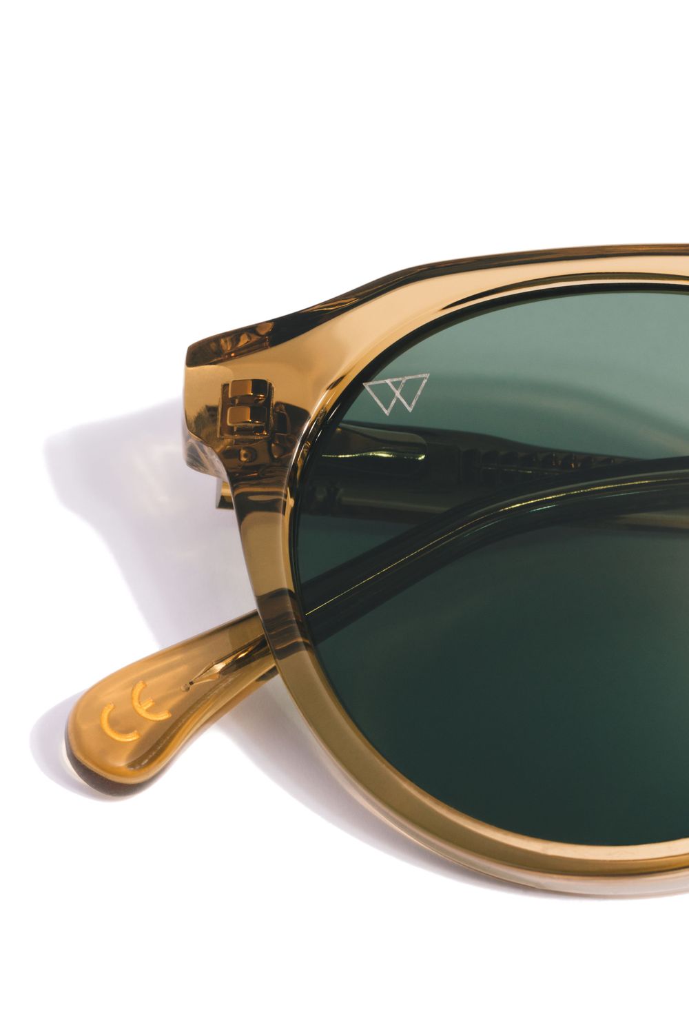 Close-up detail of amber-colored transparent sunglasses frame with green lens.