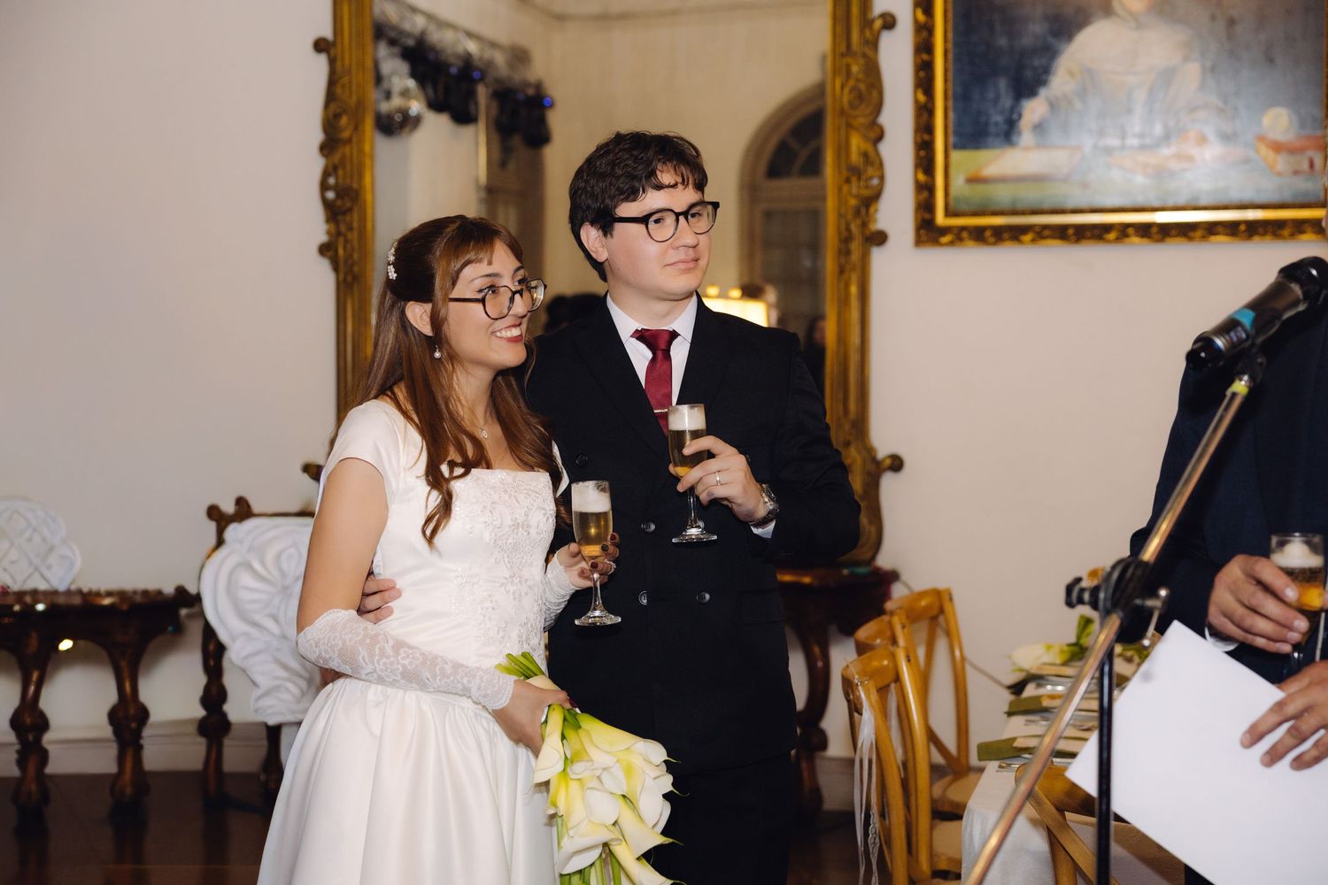 Newlywed couple toasting with champagne glasses during their wedding reception in an elegant room.
