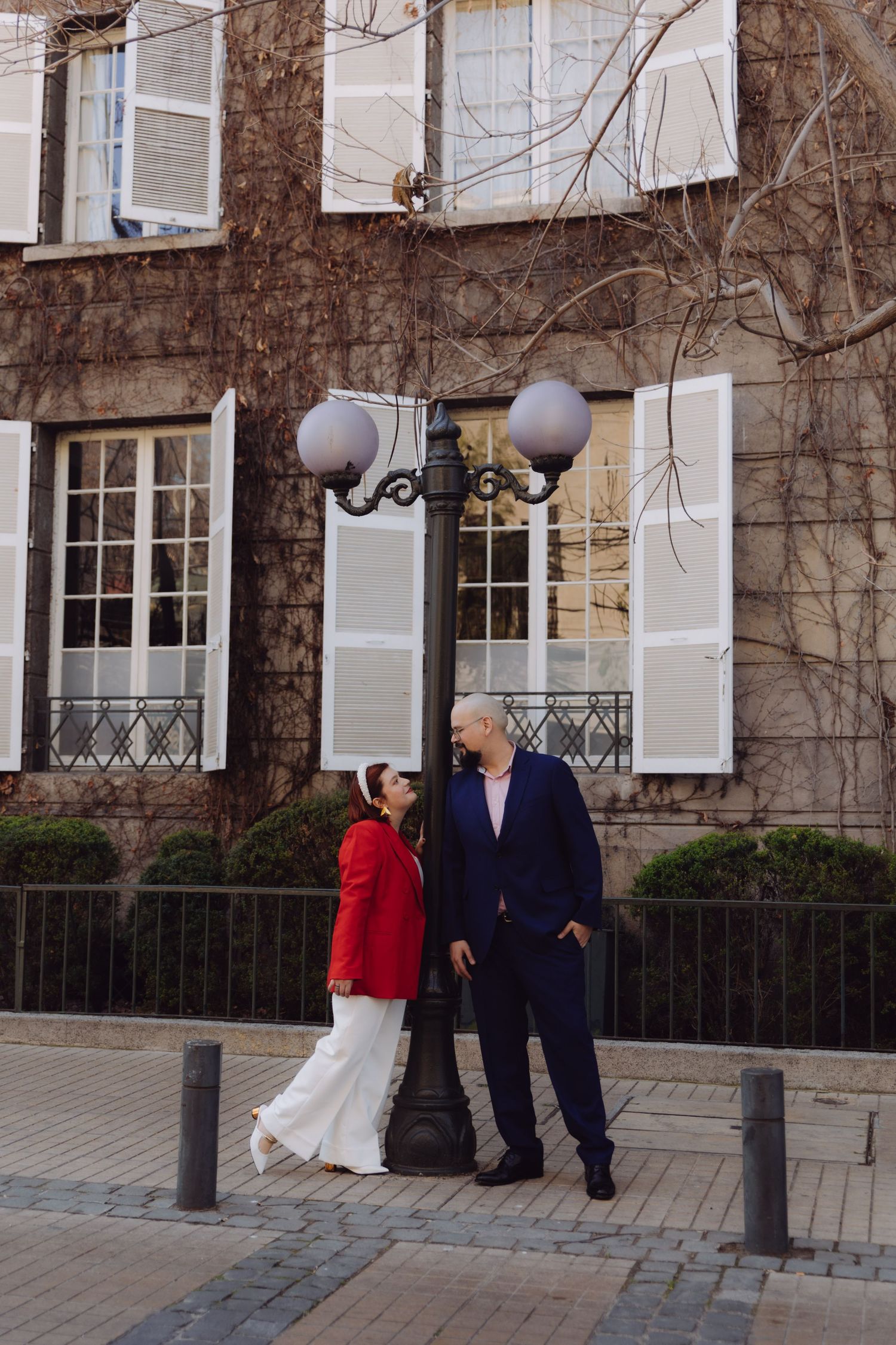 Elegant couple sharing a loving gaze beside a vintage street lamp in a European city setting.
