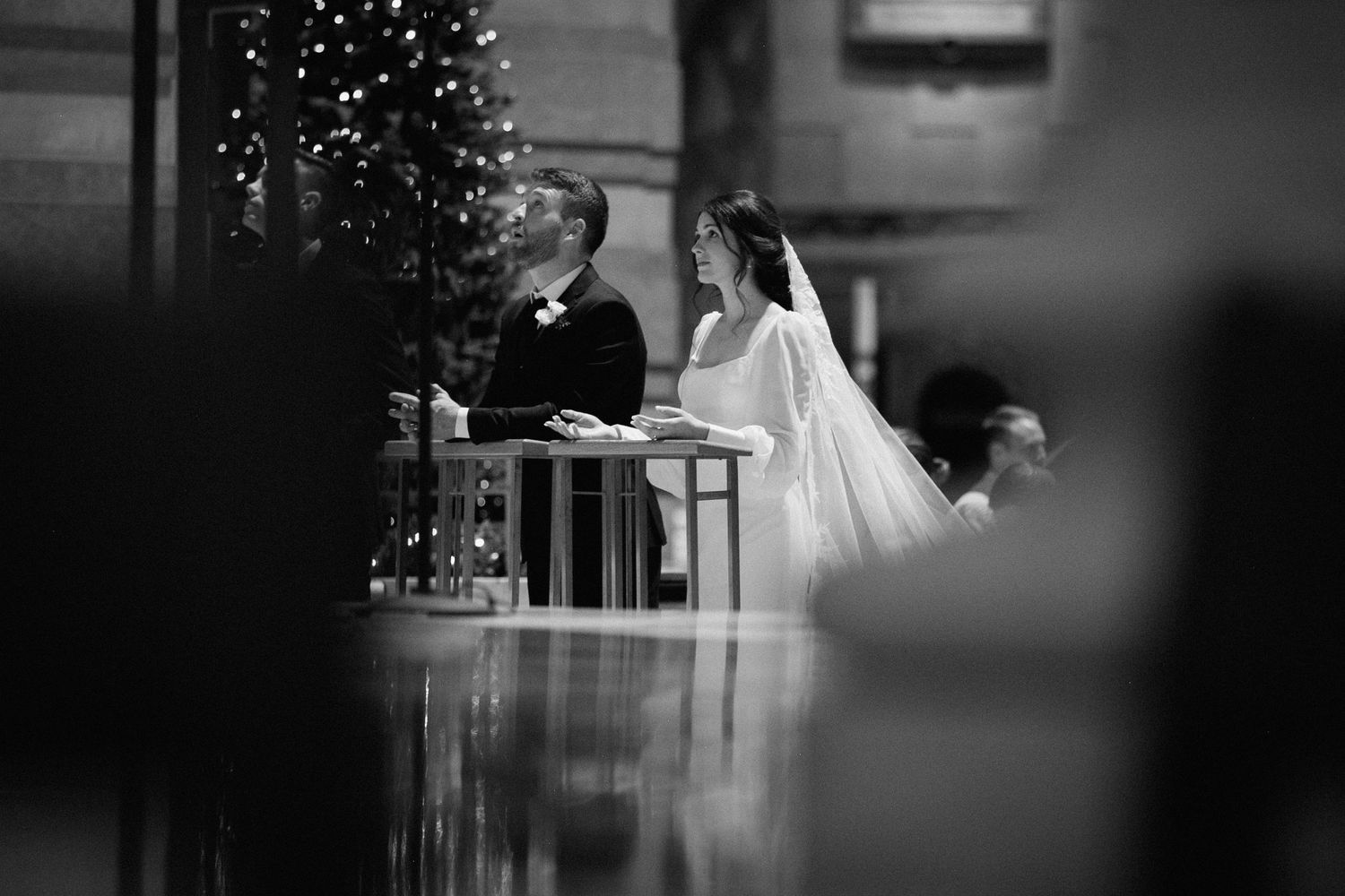 Black and white photo of wedding ceremony in church with Christmas tree.